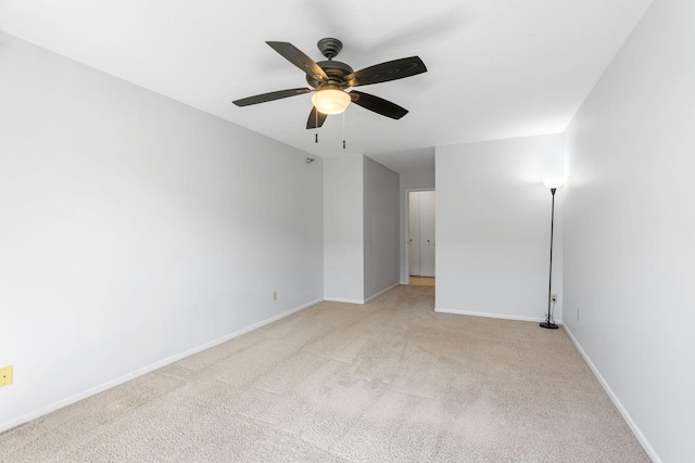 spare room featuring ceiling fan, light colored carpet, and baseboards