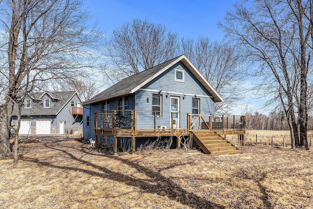 view of front facade with a deck, stairway, a garage, and a shingled roof