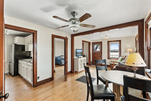 dining room with baseboards, light wood finished floors, and ceiling fan