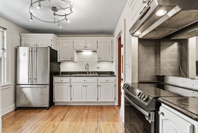 kitchen featuring ventilation hood, freestanding refrigerator, light wood-style floors, electric stove, and a sink