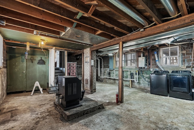 basement featuring a wood stove, washing machine and dryer, and water heater