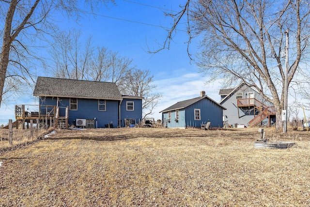 rear view of house with roof with shingles, a deck, and stairs