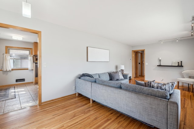 living room with track lighting, baseboards, and light wood-type flooring