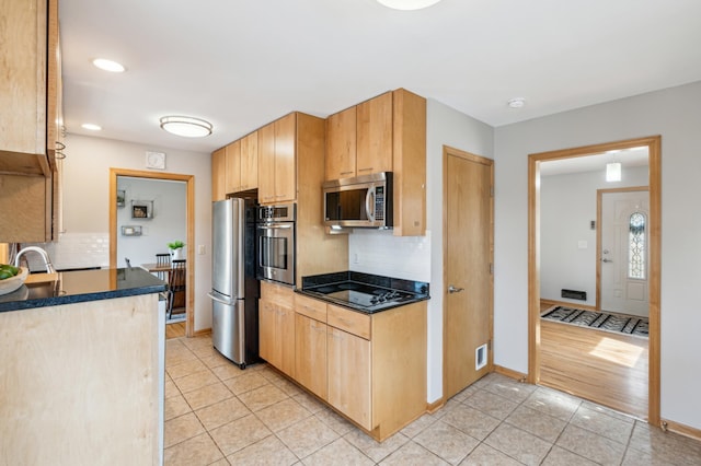 kitchen featuring light tile patterned floors, stainless steel appliances, dark countertops, and light brown cabinetry