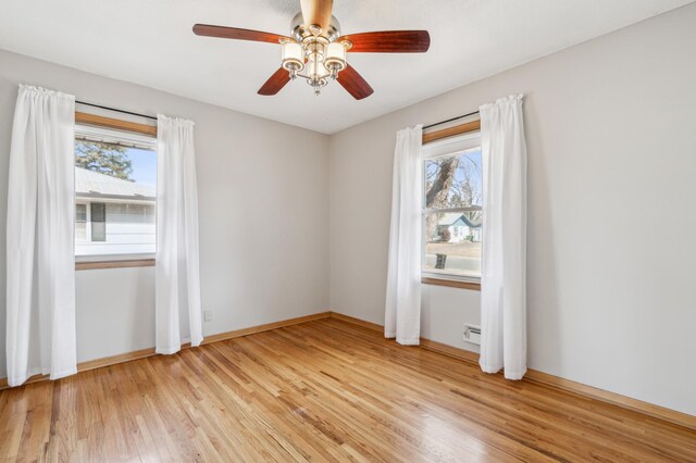 spare room featuring a healthy amount of sunlight, baseboards, light wood finished floors, and ceiling fan