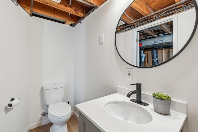 bathroom with vanity, toilet, wood finished floors, and baseboards