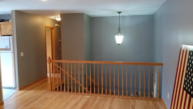 hallway featuring an upstairs landing and light wood-style floors