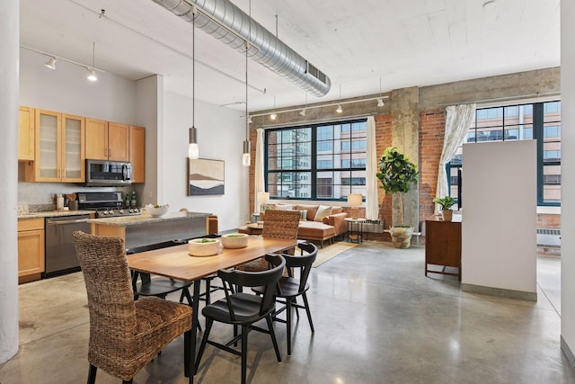 250 Park Ave Unit 606, Minneapolis, MN 55415 - dining room featuring concrete flooring, radiator, healthy amount of natural light, a towering ceiling, and brick wall