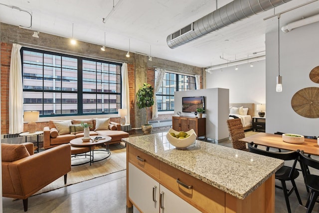250 Park Ave Unit 606, Minneapolis, MN 55415 - kitchen featuring track lighting, open floor plan, brick wall, light stone counters, and a kitchen island
