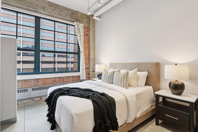 250 Park Ave Unit 606, Minneapolis, MN 55415 - bedroom with radiator heating unit, brick wall, and track lighting
