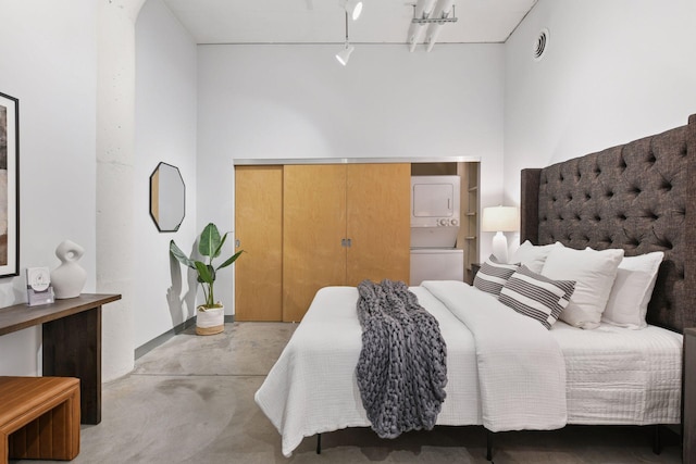 250 Park Ave Unit 606, Minneapolis, MN 55415 - bedroom featuring stacked washing machine and dryer, concrete flooring, a closet, and track lighting