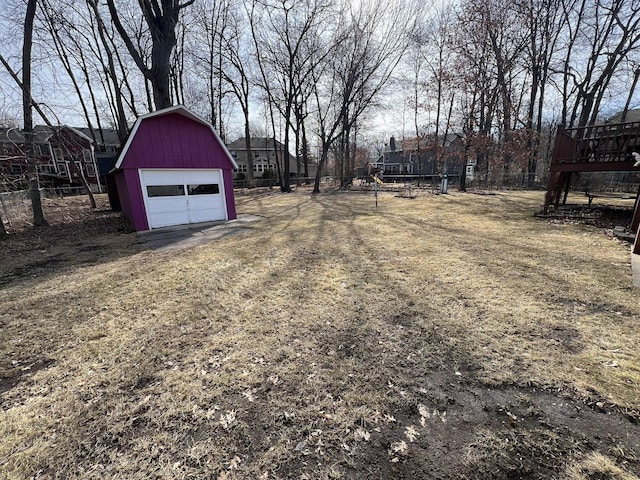 view of yard with a barn, a detached garage, an outdoor structure, and fence