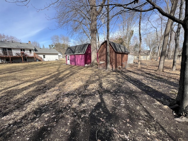 view of yard featuring an outdoor structure, a storage unit, and a wooden deck