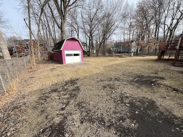 view of yard featuring a barn, a detached garage, fence, an outdoor structure, and driveway