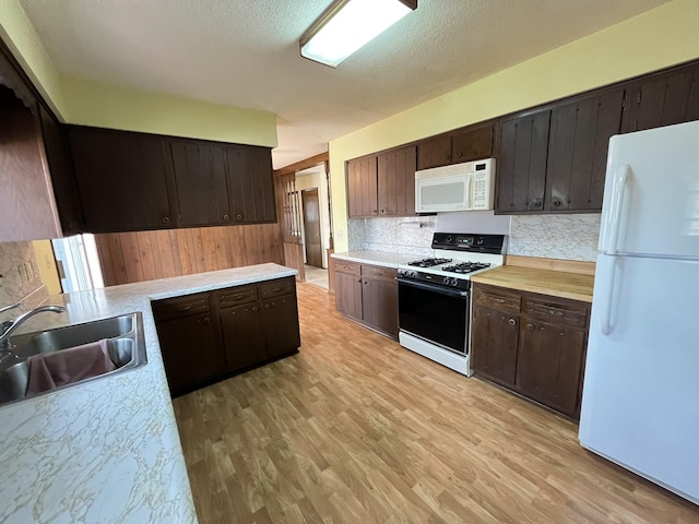 kitchen with white appliances, light countertops, light wood-type flooring, and a sink