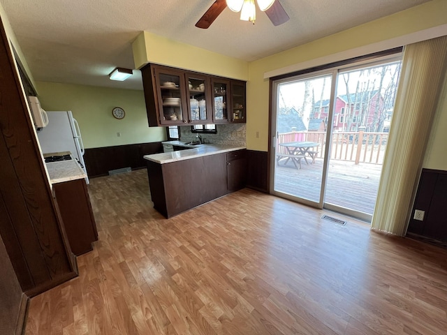 kitchen with visible vents, glass insert cabinets, dark brown cabinetry, light countertops, and a peninsula