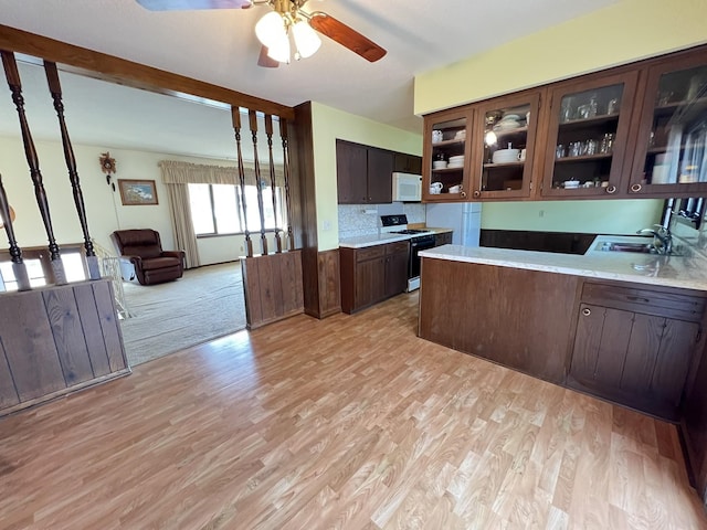 kitchen with a ceiling fan, white microwave, a sink, dark brown cabinetry, and range with gas cooktop