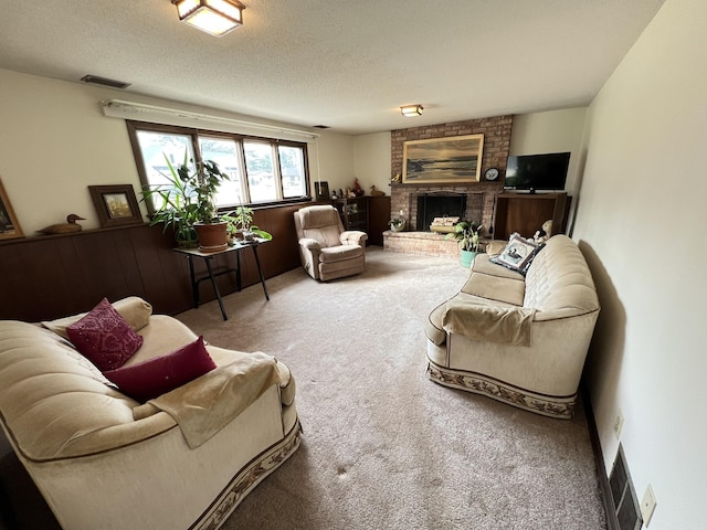 carpeted living area with visible vents, a brick fireplace, and a textured ceiling