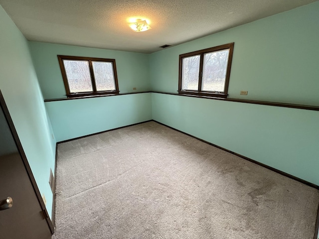 unfurnished room featuring visible vents, baseboards, carpet, and a textured ceiling