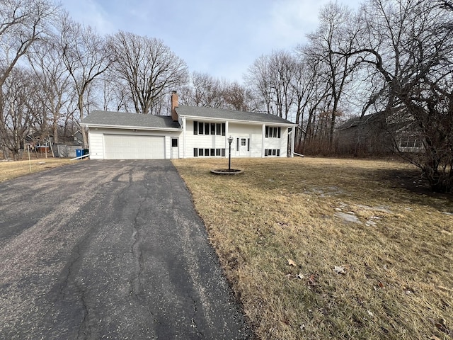 view of front of house featuring a front lawn, a garage, driveway, and a chimney