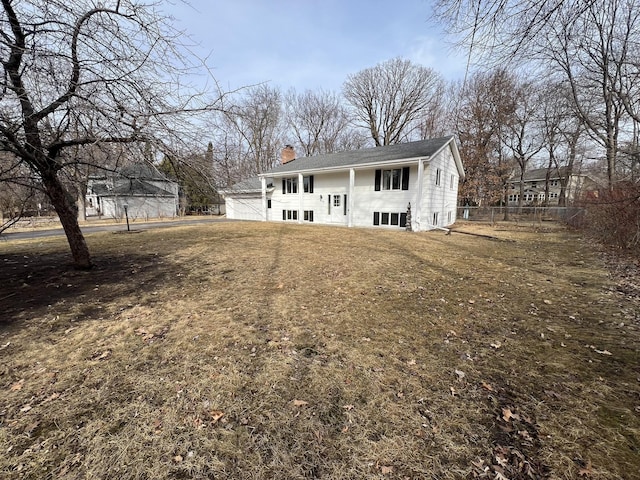 view of front of home with a front yard, a chimney, and fence