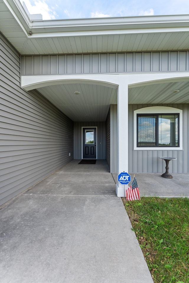 property entrance featuring a porch, a carport, and board and batten siding