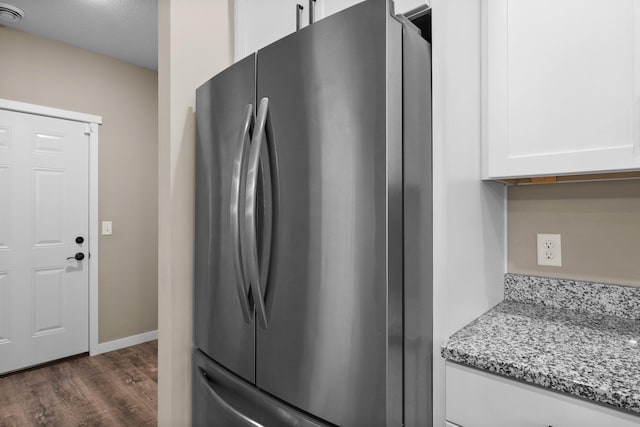 kitchen with light stone counters, dark wood finished floors, white cabinetry, and freestanding refrigerator