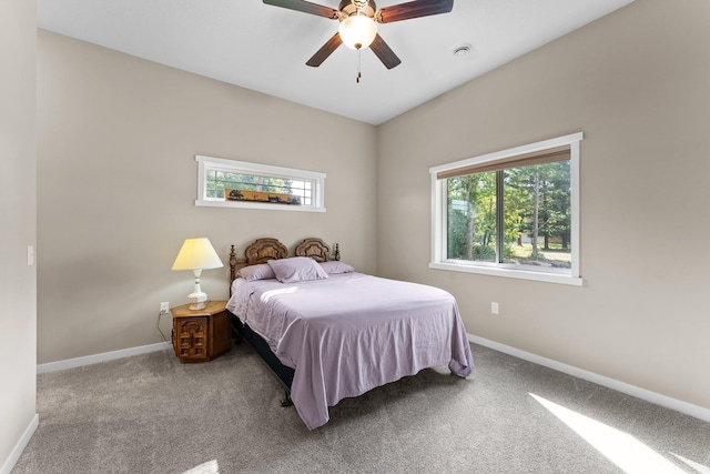 carpeted bedroom with multiple windows, a ceiling fan, and baseboards