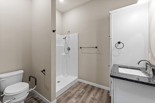 full bathroom with vanity, wood finished floors, baseboards, walk in shower, and toilet