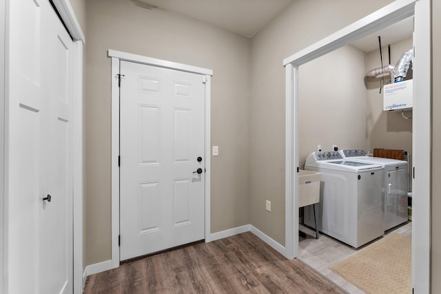 washroom featuring washer and clothes dryer, laundry area, baseboards, and wood finished floors