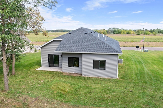 rear view of property with a patio area, a lawn, and roof with shingles