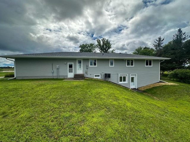 back of house featuring entry steps, central AC unit, and a lawn