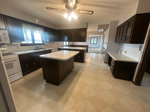 kitchen with white appliances, ceiling fan, a sink, light countertops, and a center island