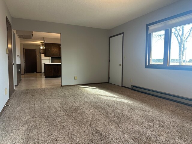 unfurnished room with light carpet, a baseboard heating unit, and baseboards