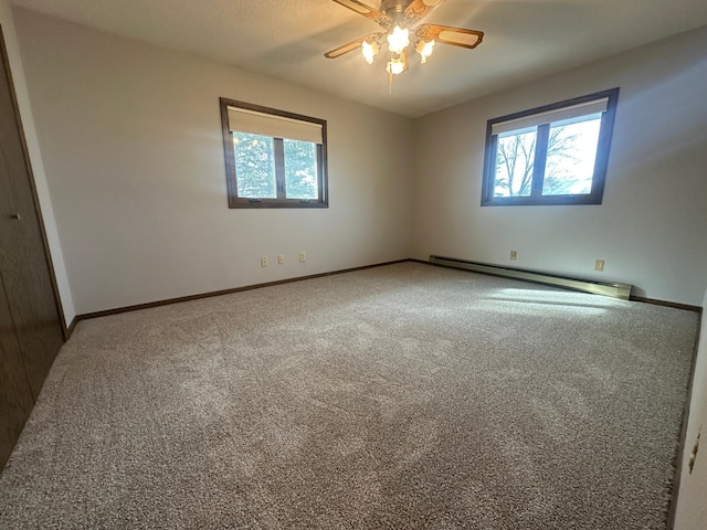 empty room featuring a baseboard heating unit, plenty of natural light, baseboards, and carpet floors