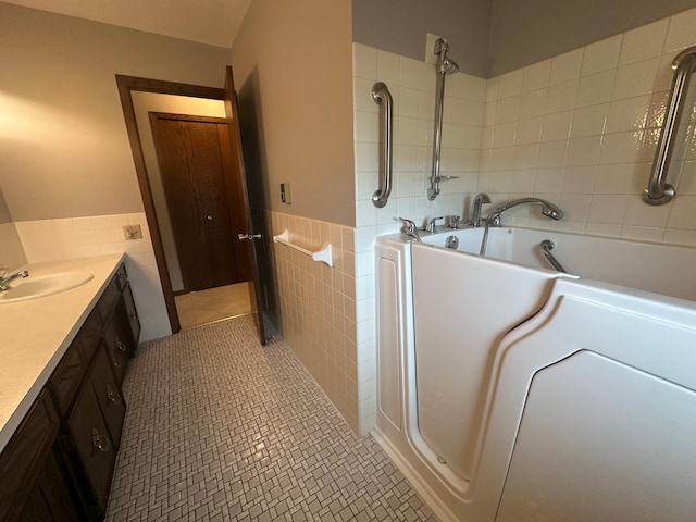 bathroom featuring tile patterned floors, a washtub, tile walls, and vanity