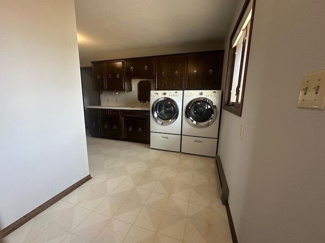 clothes washing area with cabinet space, independent washer and dryer, and baseboards