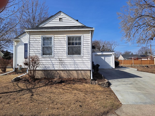 view of side of property featuring an outbuilding, concrete driveway, fence, and a detached garage