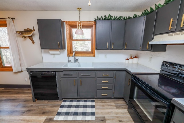 kitchen with black appliances, under cabinet range hood, a sink, light wood-style floors, and light countertops