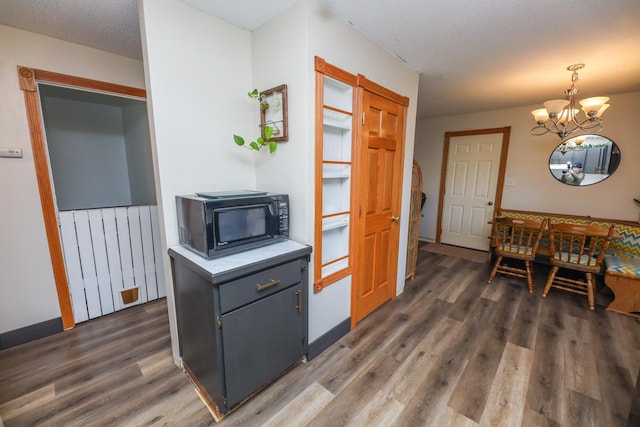 kitchen with black microwave, a chandelier, dark wood finished floors, light countertops, and hanging light fixtures