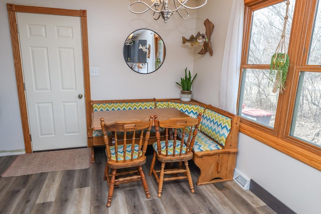 dining space with wood finished floors, visible vents, baseboards, a notable chandelier, and breakfast area