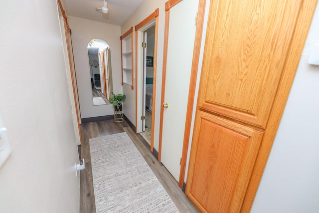 hallway with arched walkways and light wood finished floors