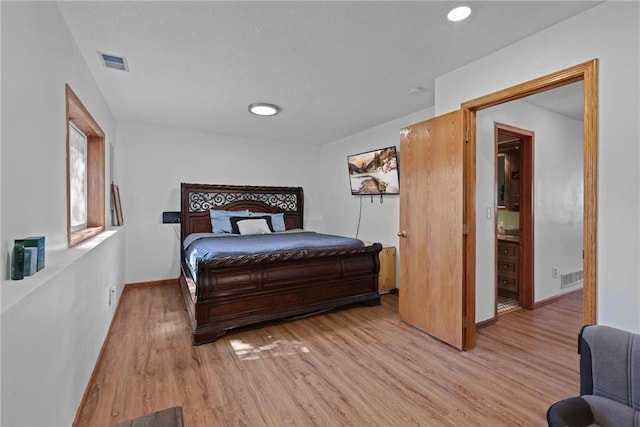 bedroom with light wood finished floors, visible vents, and baseboards