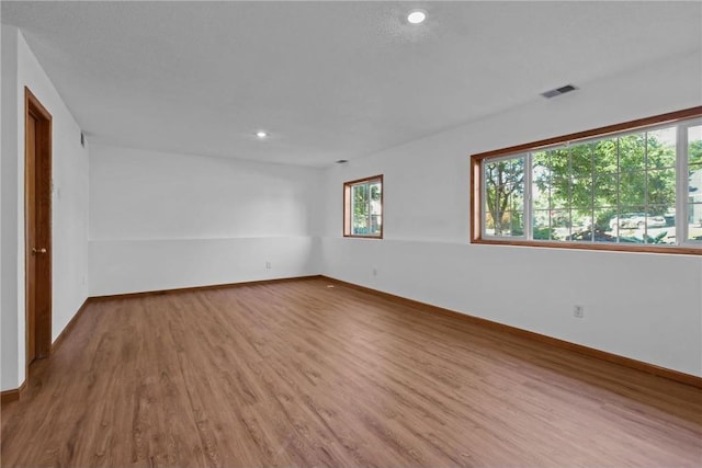 unfurnished room featuring wood finished floors, visible vents, and baseboards