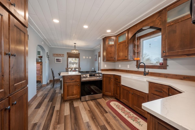 kitchen featuring arched walkways, plenty of natural light, stainless steel range with electric stovetop, and a sink