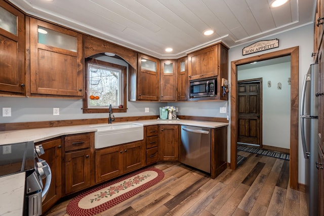 kitchen featuring dark wood-style floors, recessed lighting, a sink, glass insert cabinets, and appliances with stainless steel finishes