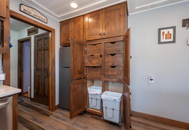 kitchen featuring brown cabinets, dark wood-type flooring, appliances with stainless steel finishes, light countertops, and baseboards