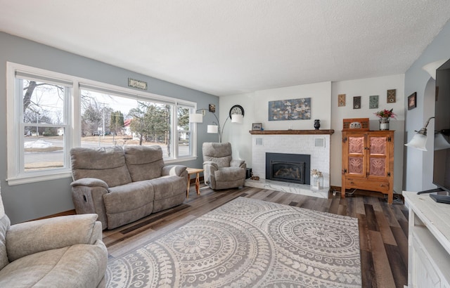 living room featuring a brick fireplace, wood finished floors, and a textured ceiling