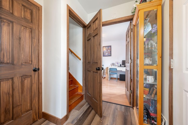 corridor featuring dark wood-style floors, stairs, and baseboards