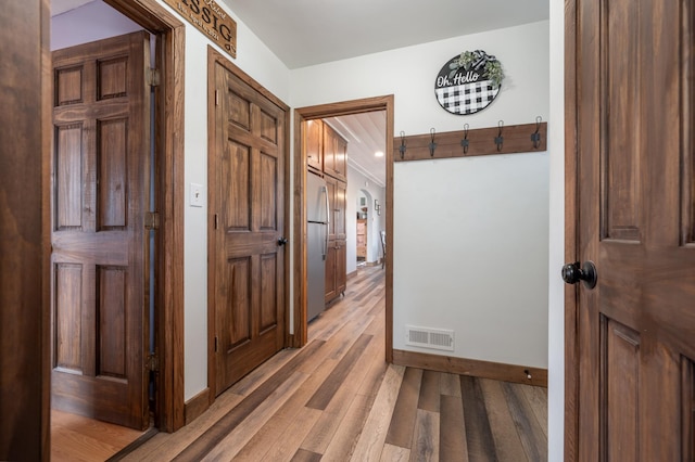 hall with baseboards, visible vents, and light wood-type flooring